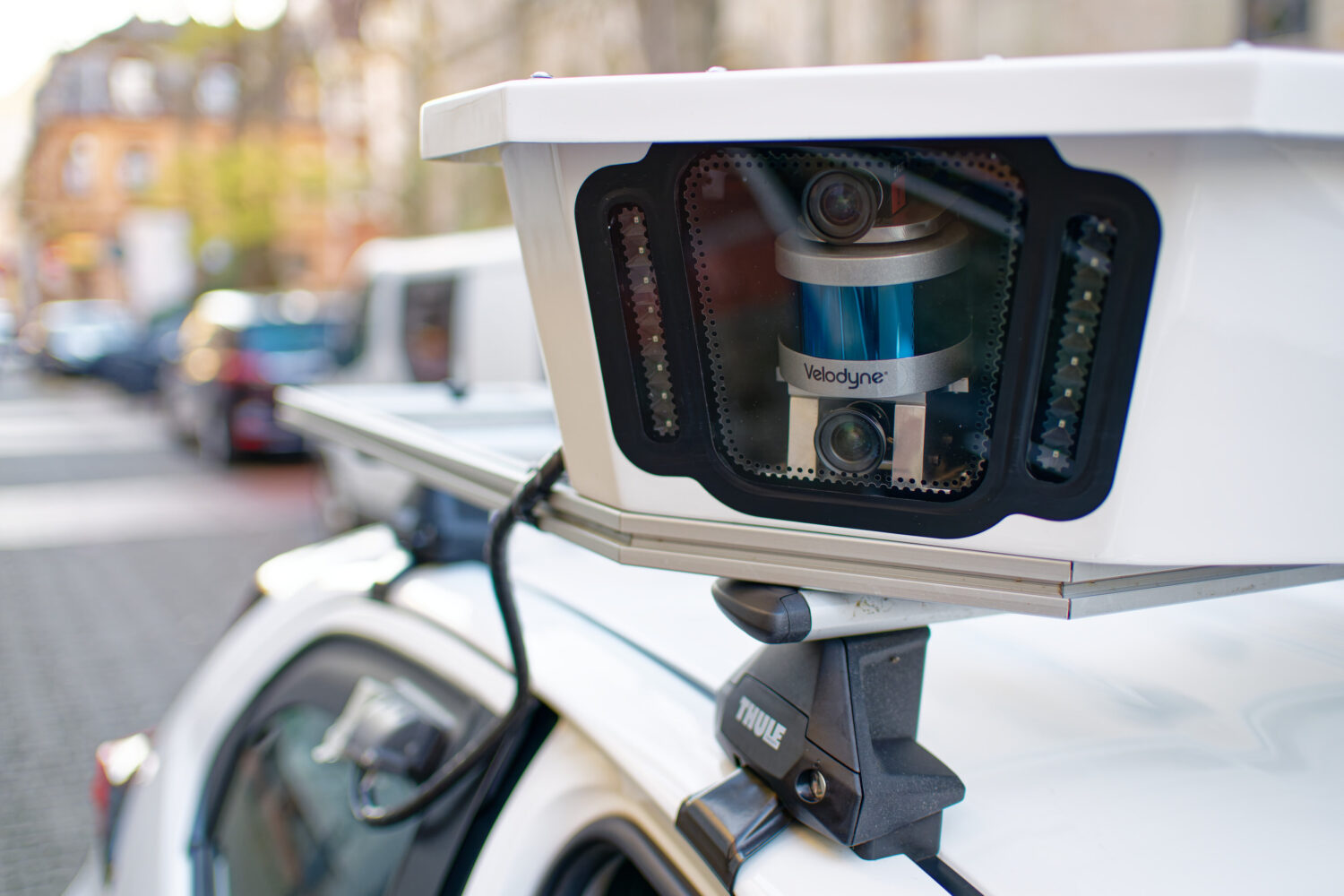 Lidar-Sensor auf Autodach in städtischer Umgebung montiert.