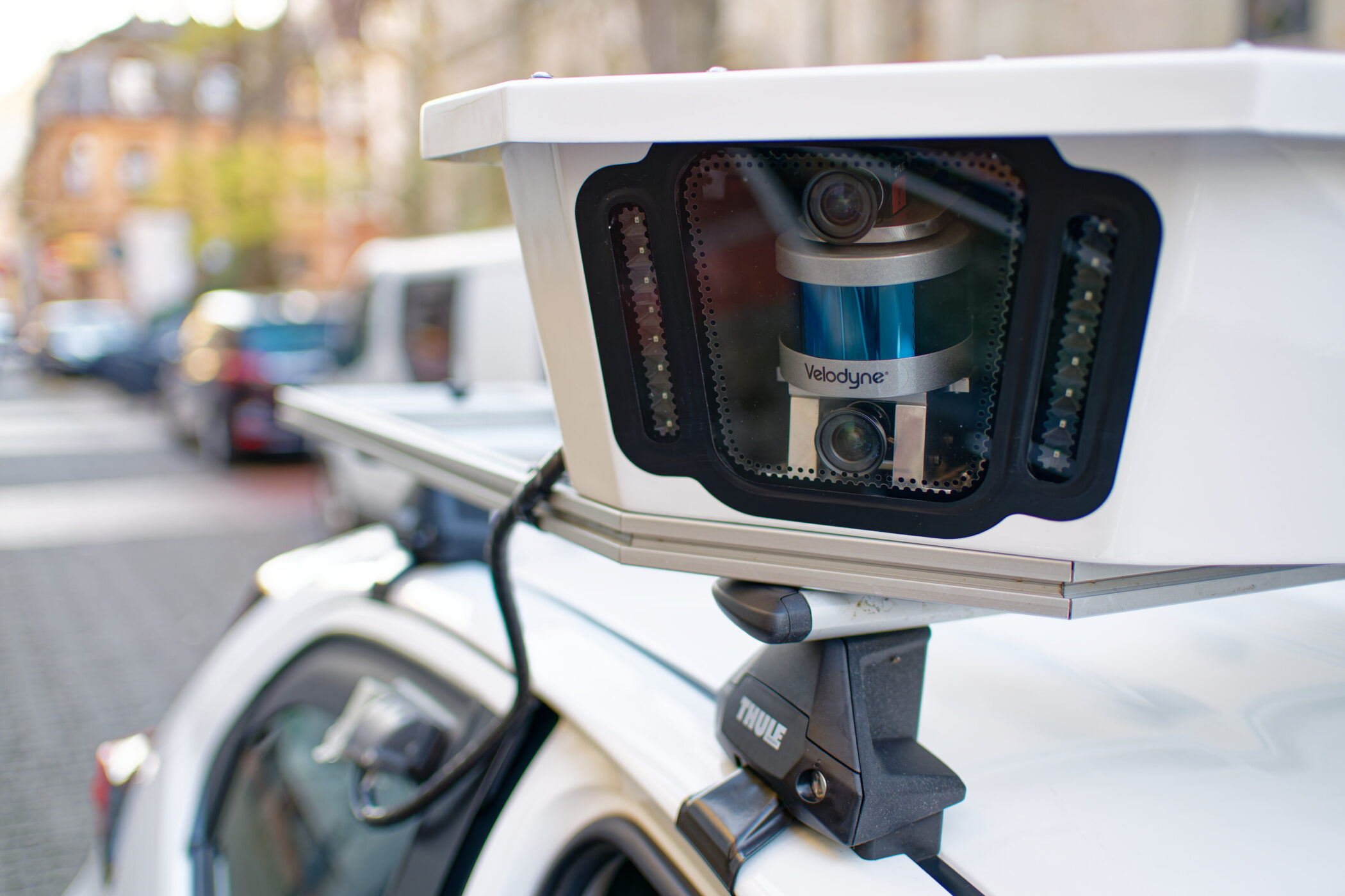 Lidar-Sensor auf Autodach in städtischer Umgebung montiert.