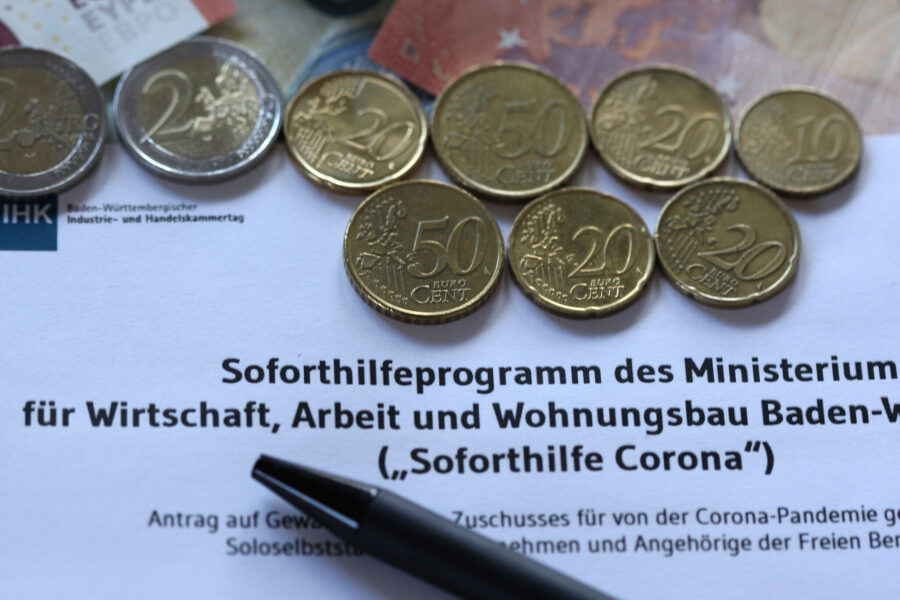 Vier 2-Euro-Münzen, fünf Cent-Münzen und ein Stift auf einem Formular.