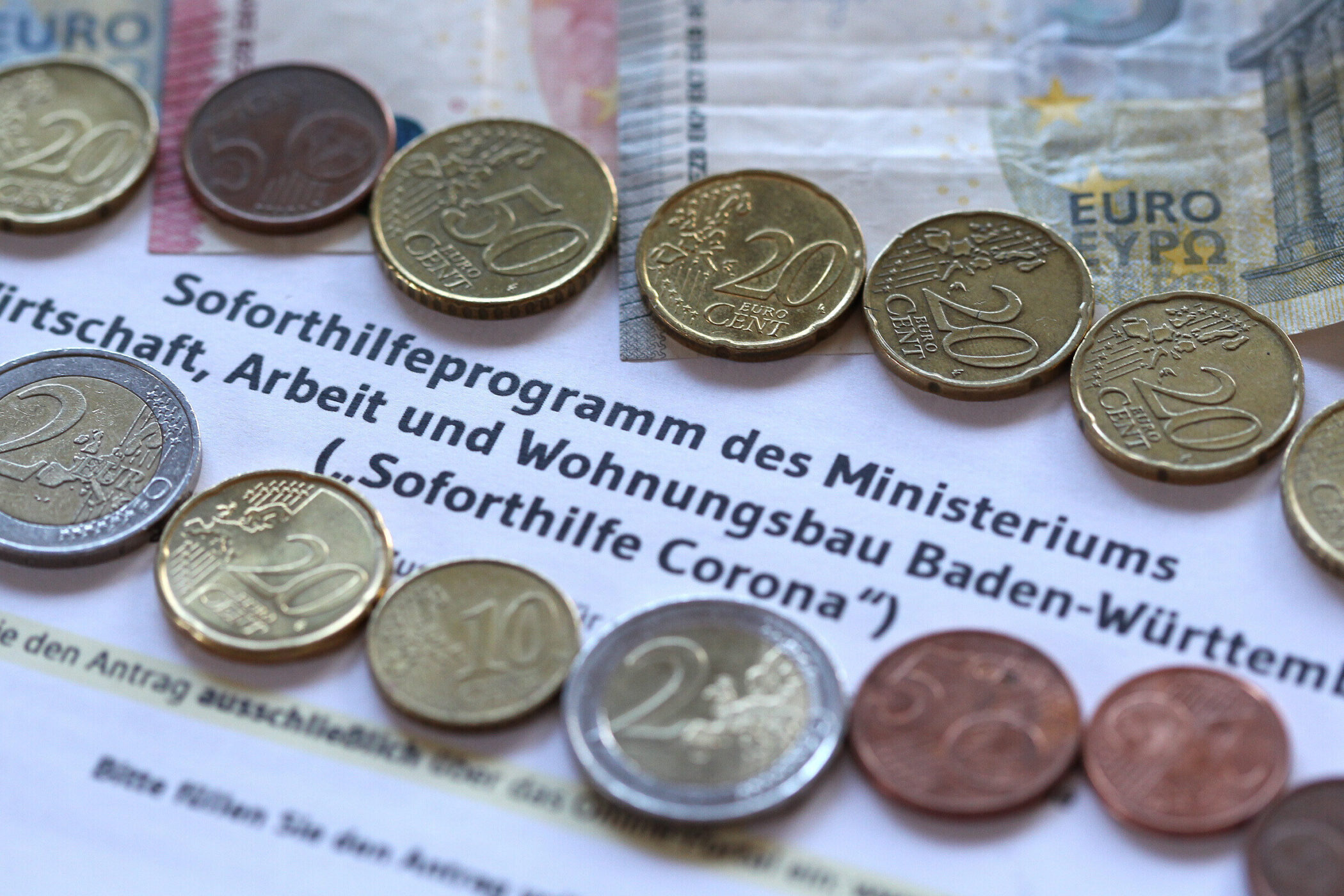 Münzen auf einem Dokument mit dem Text "Soforthilfeprogramm des Ministeriums".