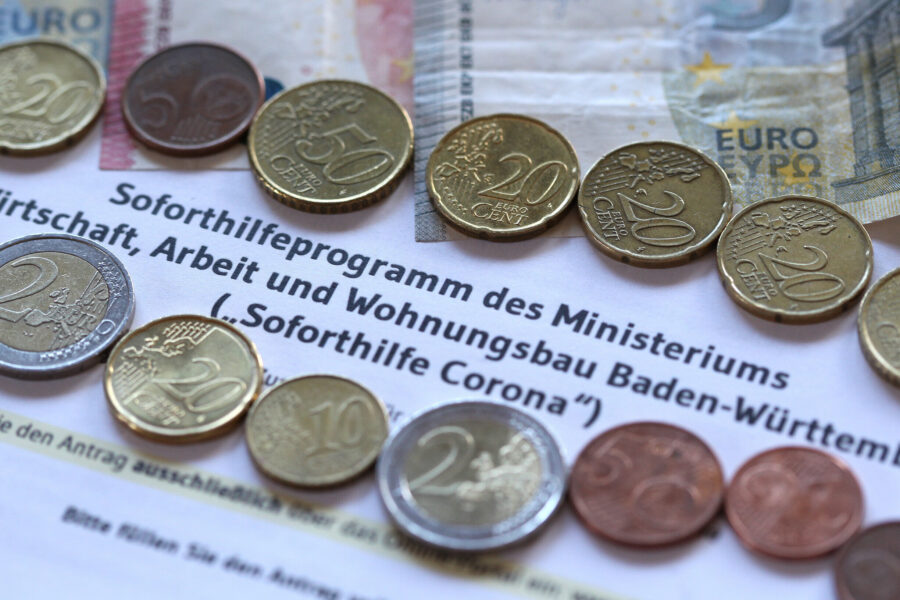 Münzen auf einem Dokument mit dem Text "Soforthilfeprogramm des Ministeriums".