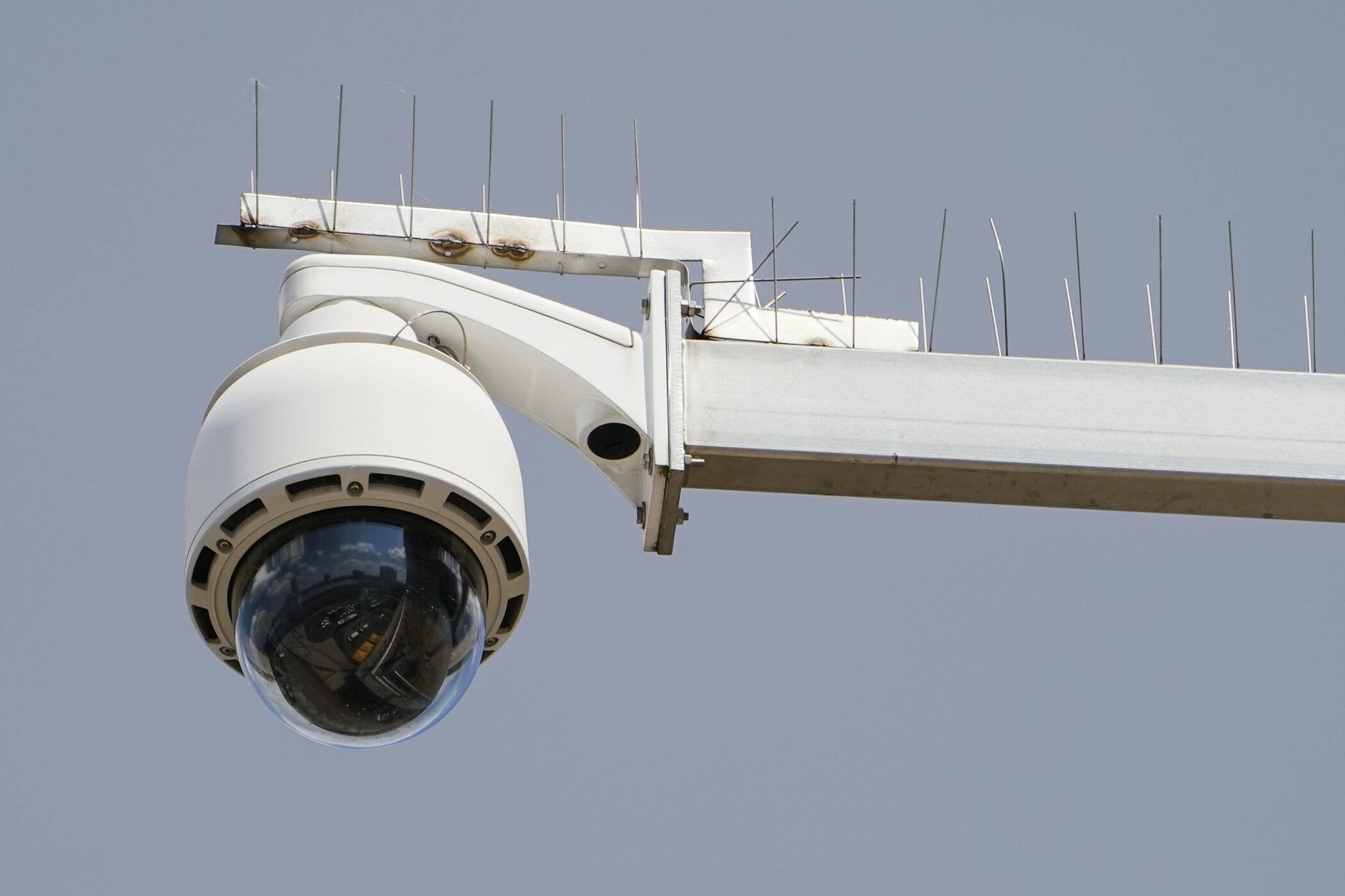Überwachungskamera an einem Metallarm mit Spikes gegen Vögel.