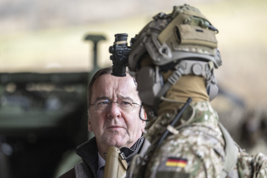 Ein Mann vor einem Soldaten in Tarnkleidung und Helm mit Kamera.