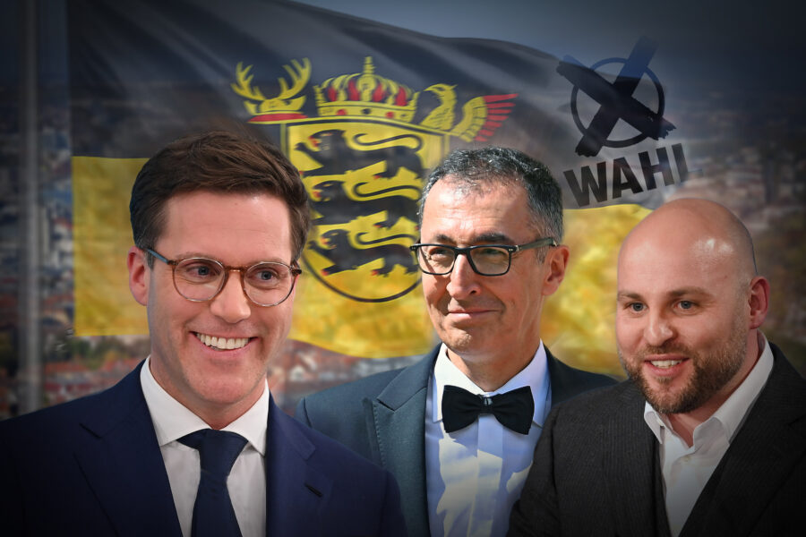 Drei Männer vor einer Fahne mit Wappen und der Aufschrift "WAHL".