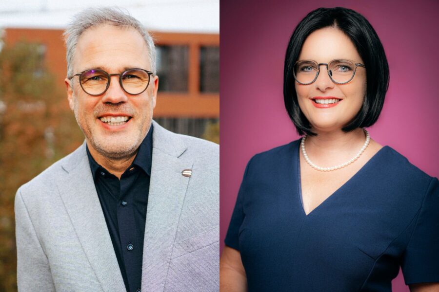 Zwei Personen mit Brillen, Mann links im grauen Anzug, Frau rechts im blauen Kleid.