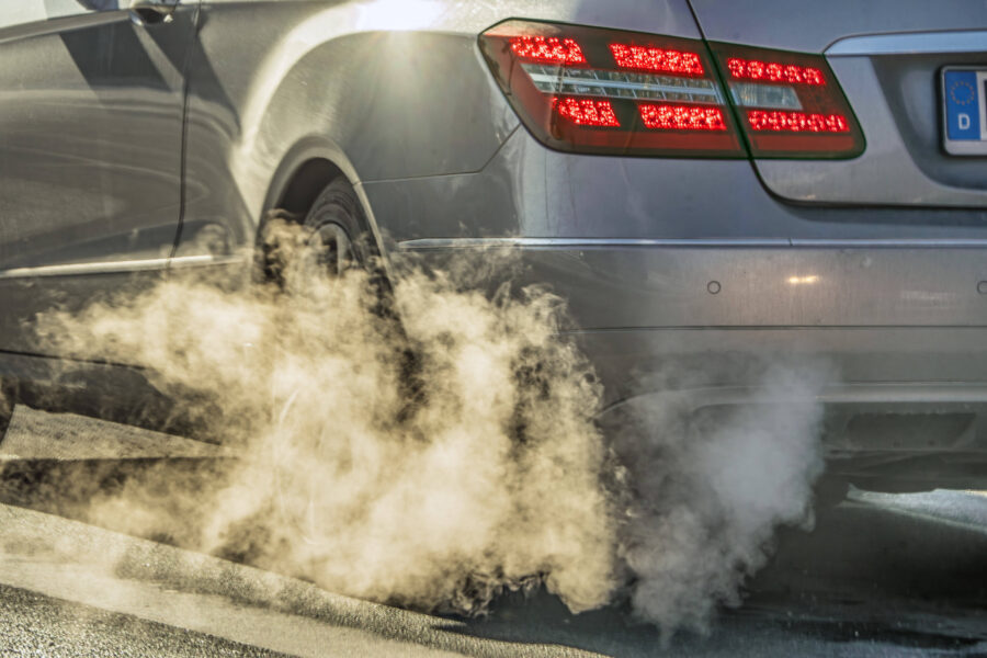 Auto mit qualmendem Auspuff, Rücklichter leuchten rot.