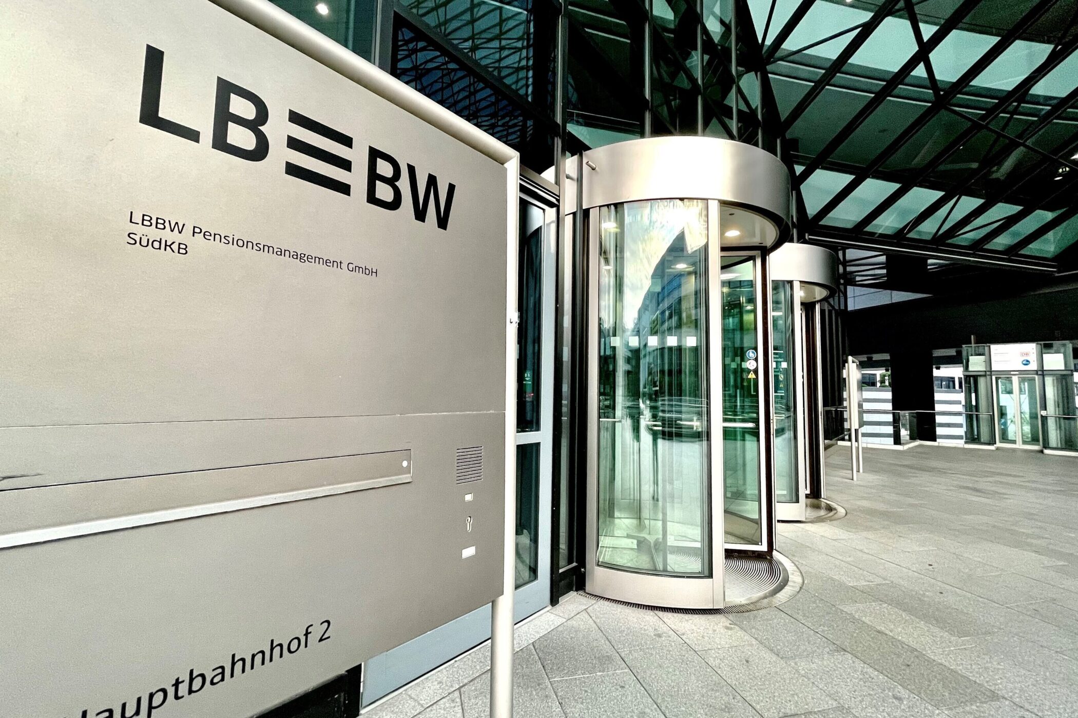 Eingang mit Drehtür zu modernem Gebäude, Schild mit Text "LBBW Pensionsmanagement GmbH".