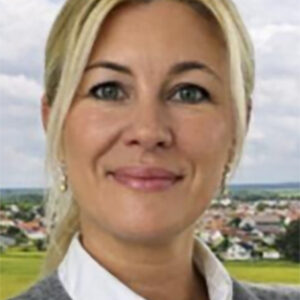 Eine lächelnde Frau vor einem Hintergrund aus Landschaft und Häusern.