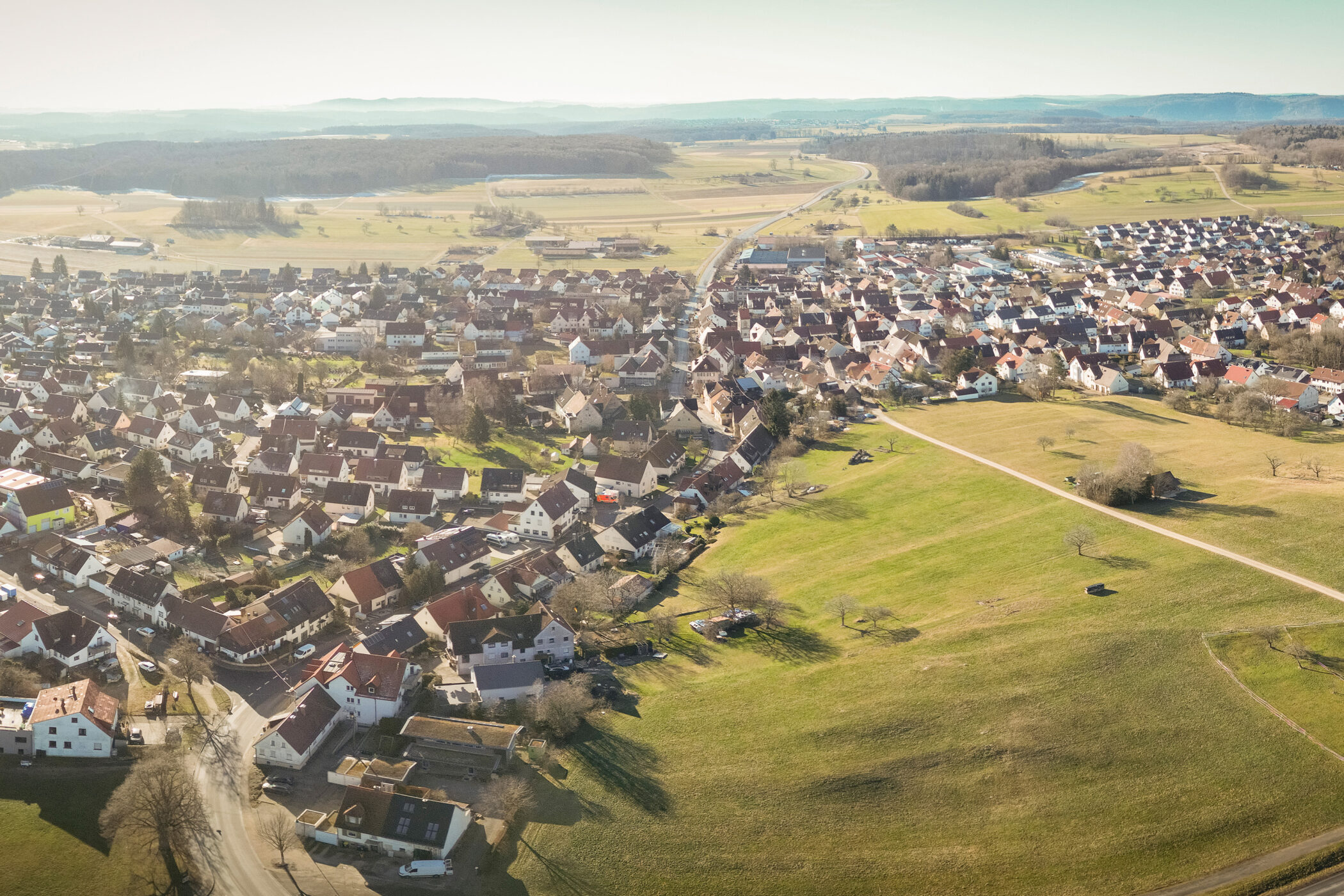 Kleinstadt aus der Luft, umgeben von Feldern und Wäldern. Häuser dicht aneinander.