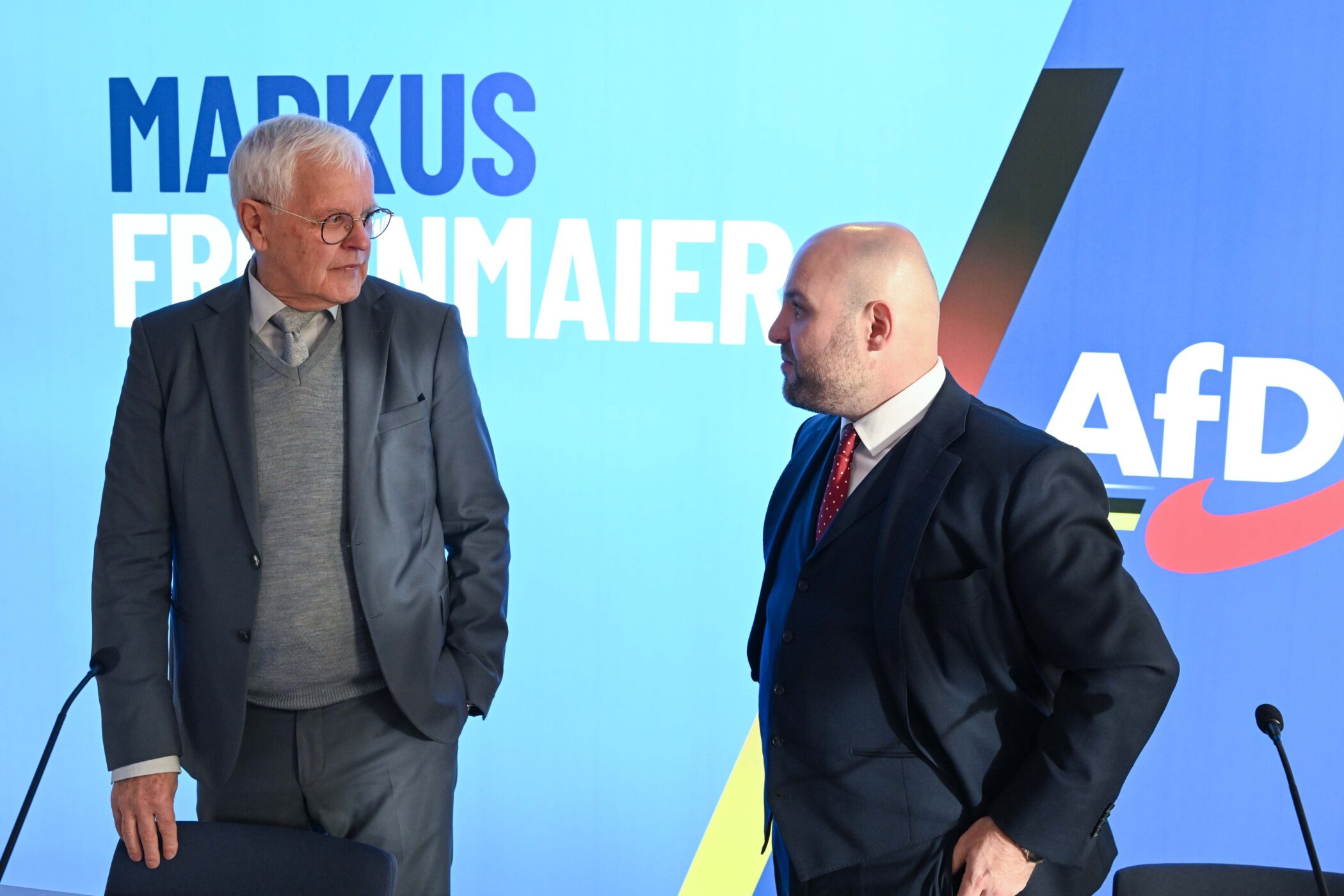 Zwei Männer in Anzügen, im Hintergrund der Text "Markus Frohnmaier" und "AfD".