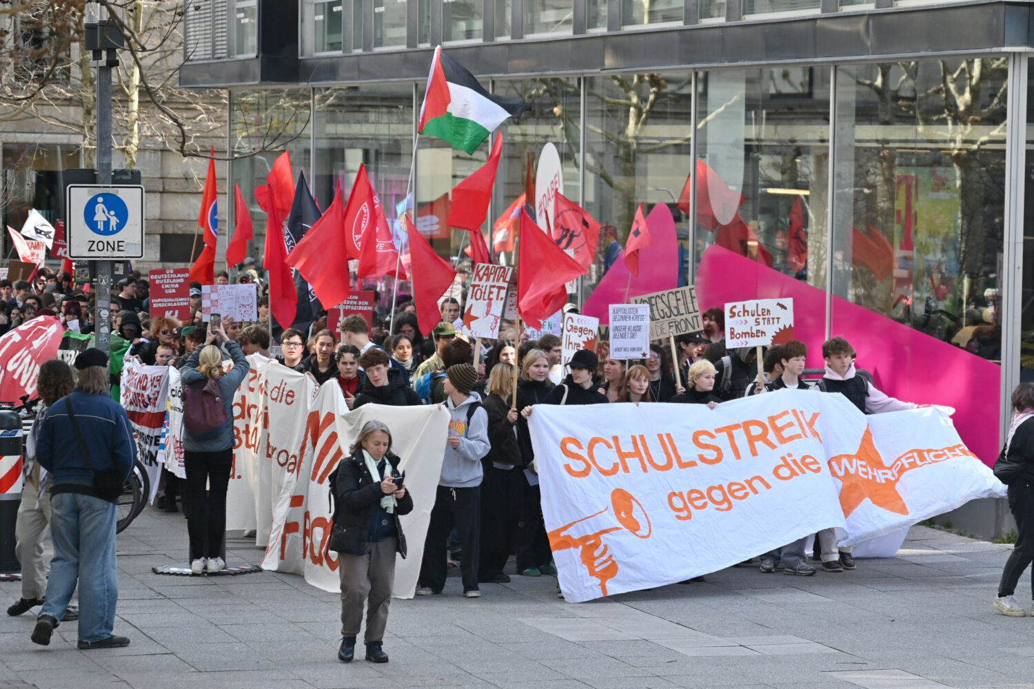 Demonstration mit Bannern, rote Fahnen, Menschenmenge, Stadtumgebung.