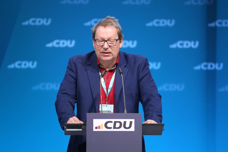 Eine Person am Rednerpult mit CDU-Logo, blauer Hintergrund.