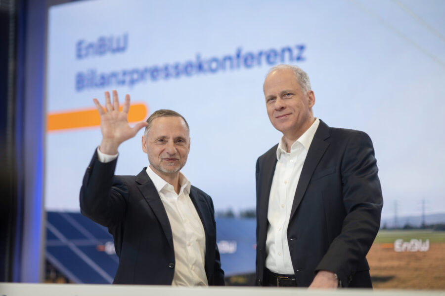 Zwei Männer in Anzügen vor einem Bildschirm, darauf der Text "EnBW Bilanzpressekonferenz".