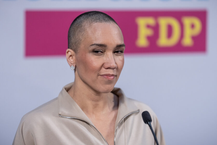 Eine Person mit kurzem Haar an einem Mikrofon, im Hintergrund Logo mit "FDP".