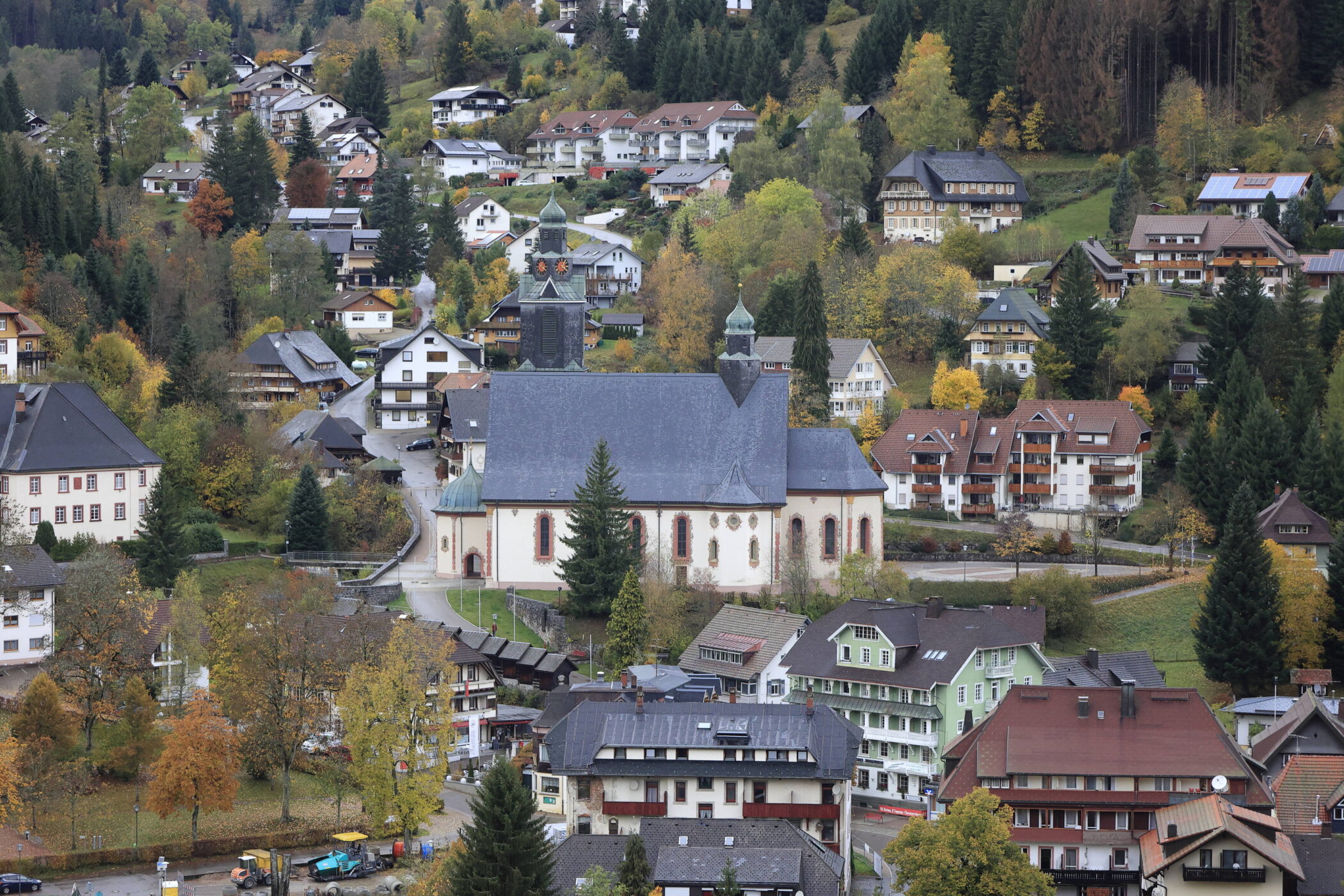 Kirche in einem Dorf mit bunt belaubten Bäumen und umliegenden Gebäuden.