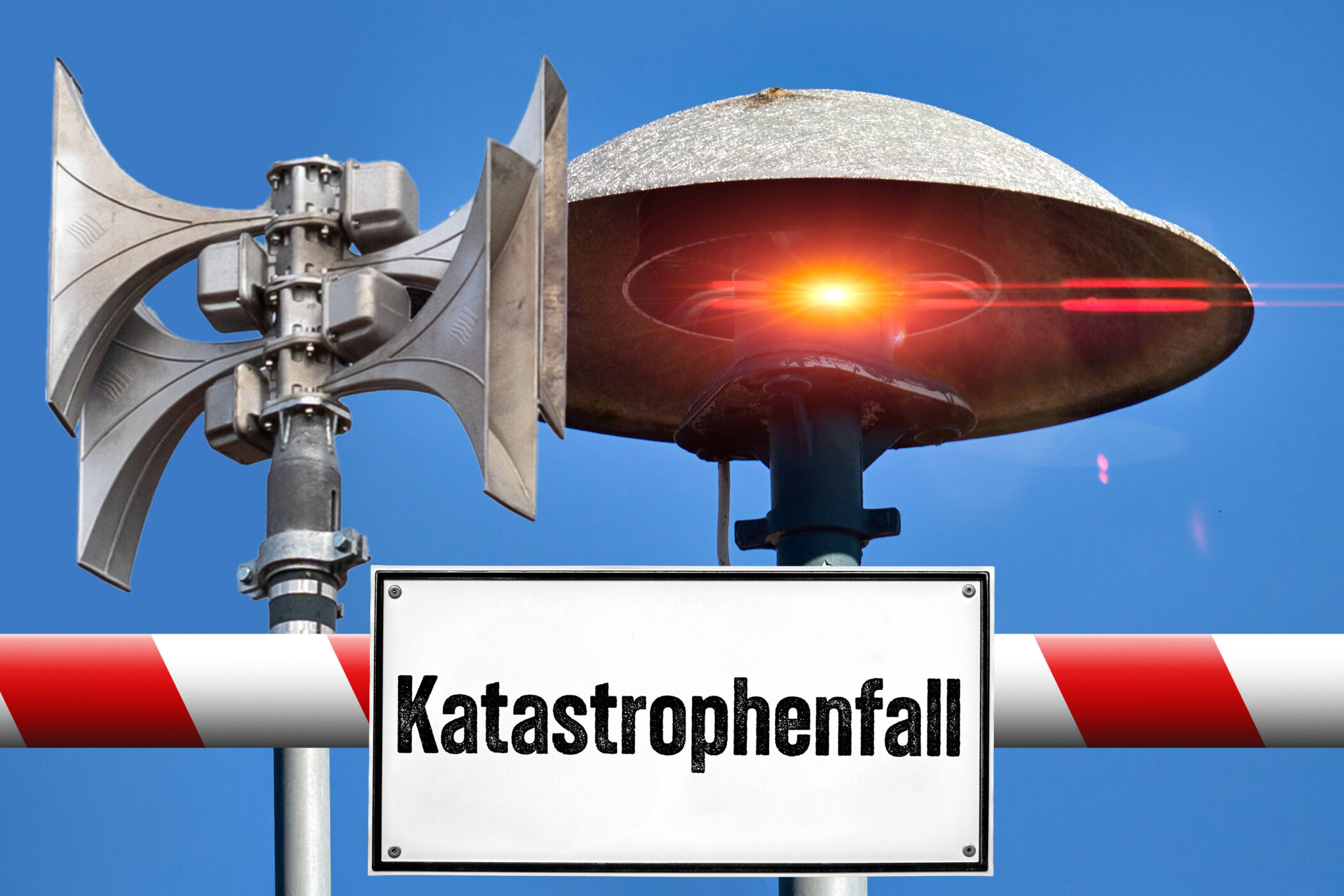 Zwei Sirenen und Schild mit "Katastrophenfall" vor blauem Himmel.