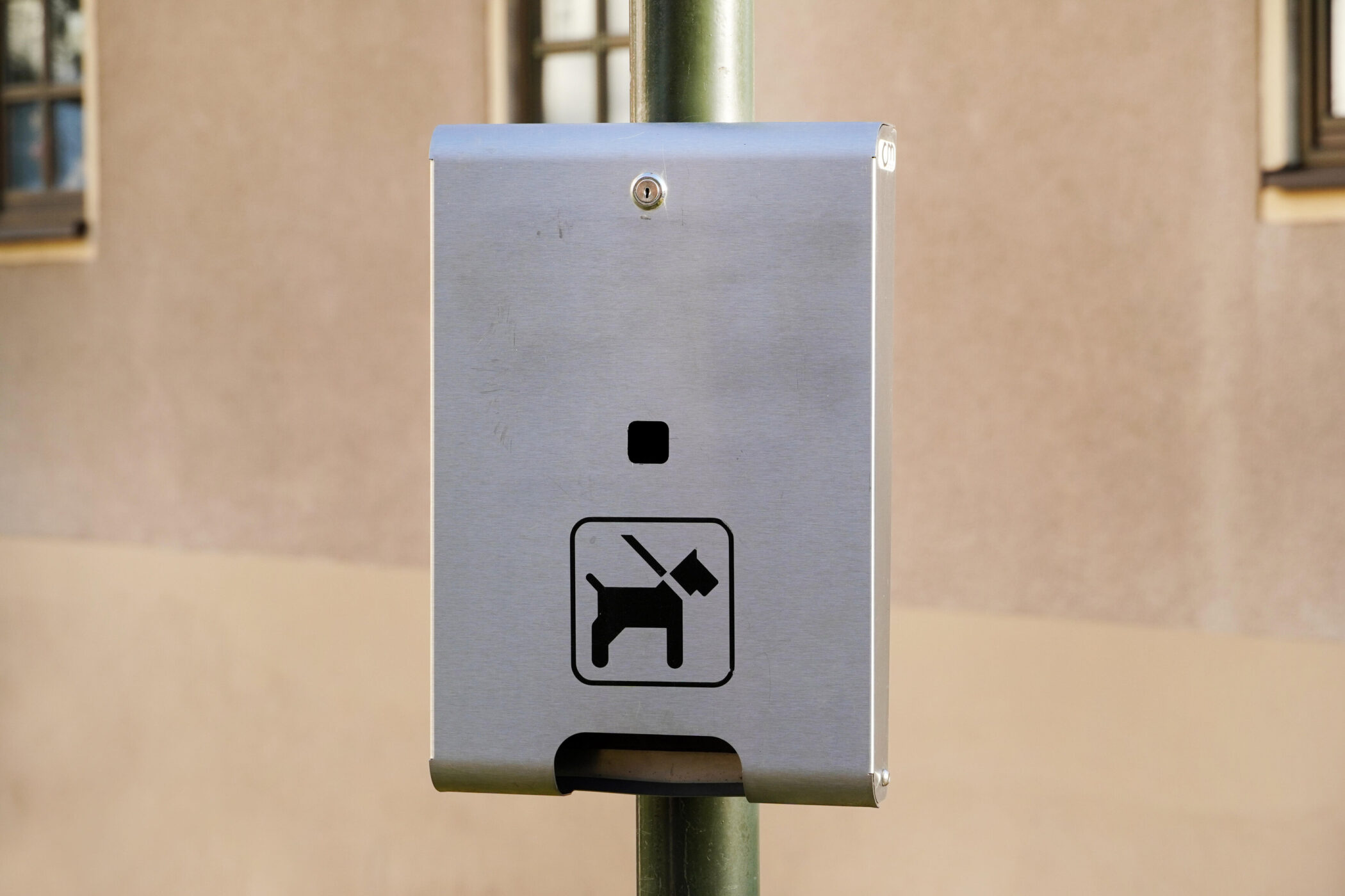 Silberne Box an einem Pfosten, Symbol eines Hundes mit Tüte darunter.