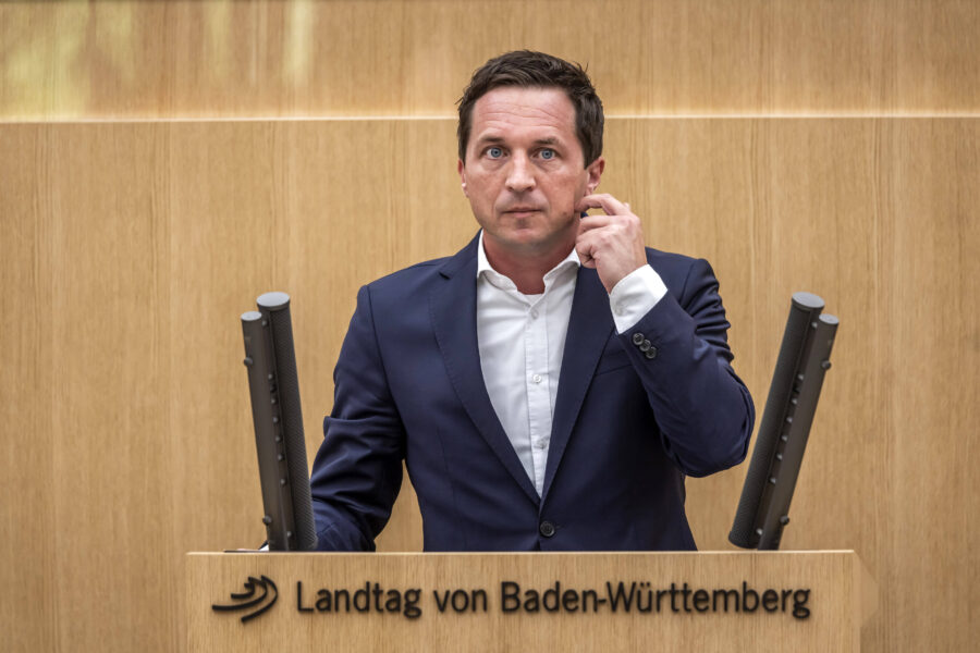 Ein Mann in Anzug hinter einem Rednerpult im Landtag von Baden-Württemberg.