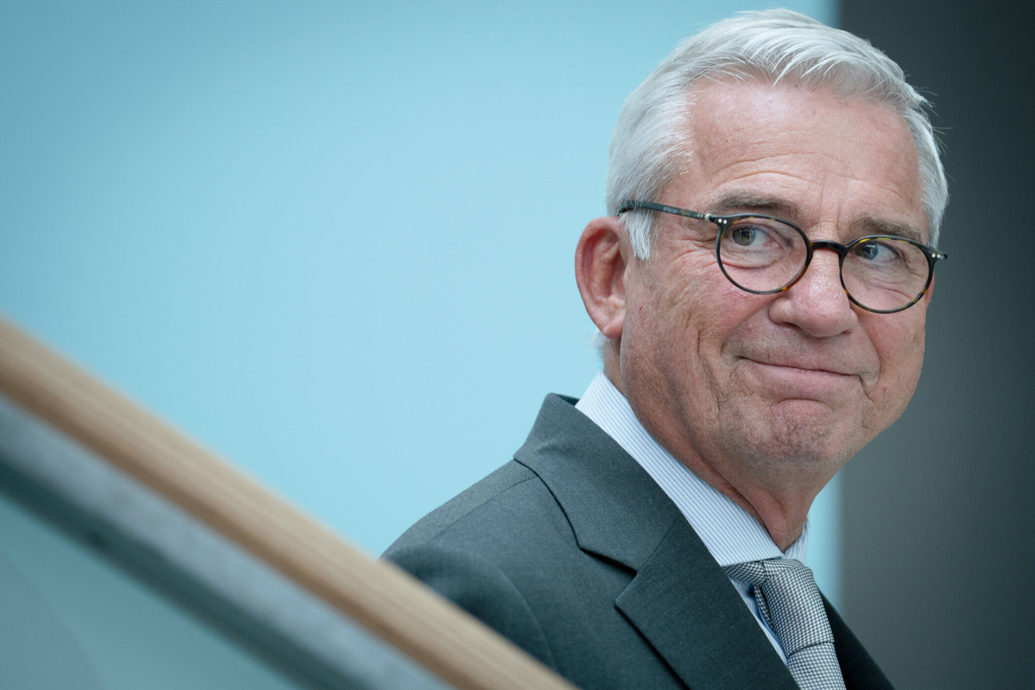 Ein älterer Mann mit Brille und Anzug blickt zur Seite.