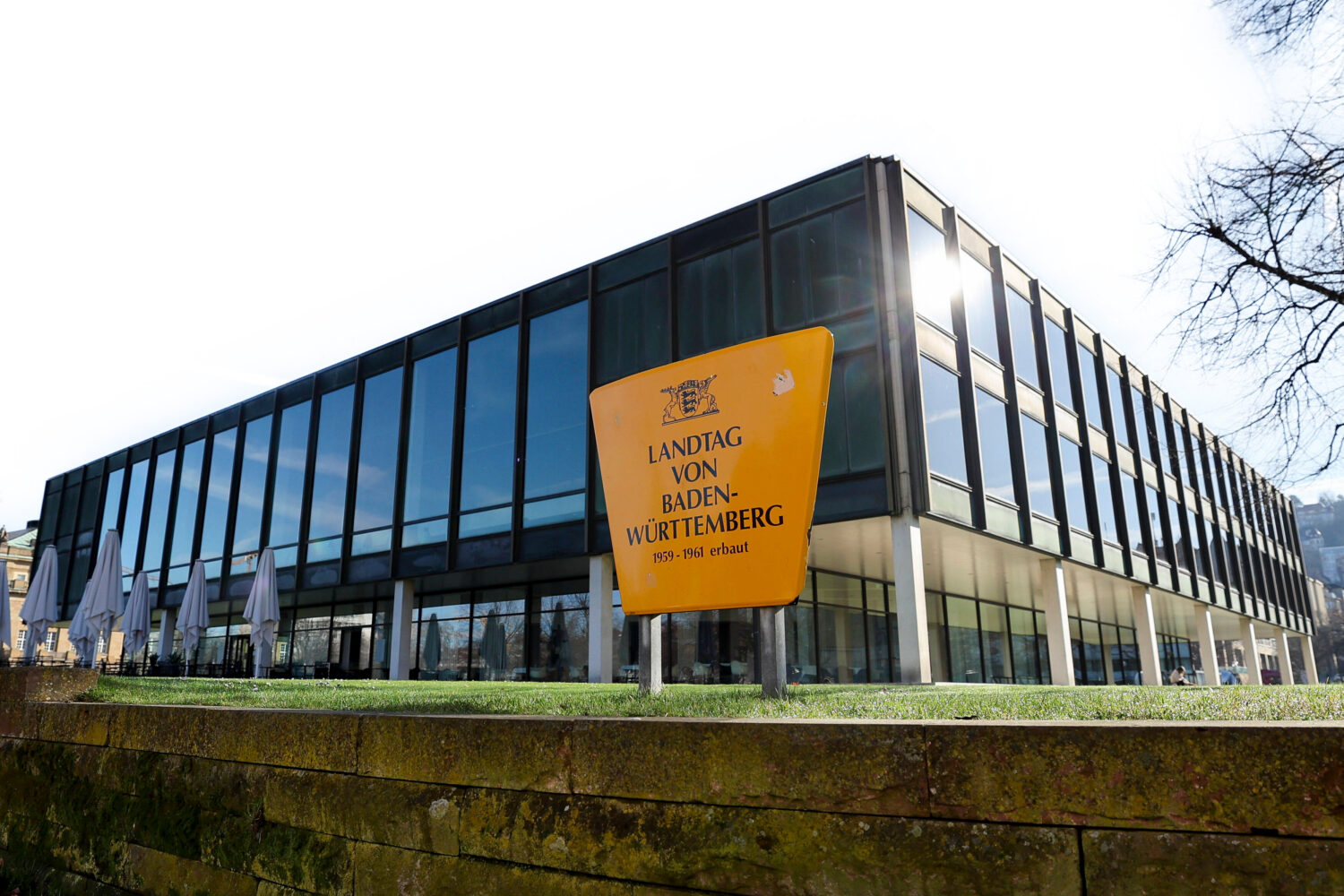 Glasgebäude mit gelbem Schild: "Landtag von Baden-Württemberg, 1959-1961 erbaut".