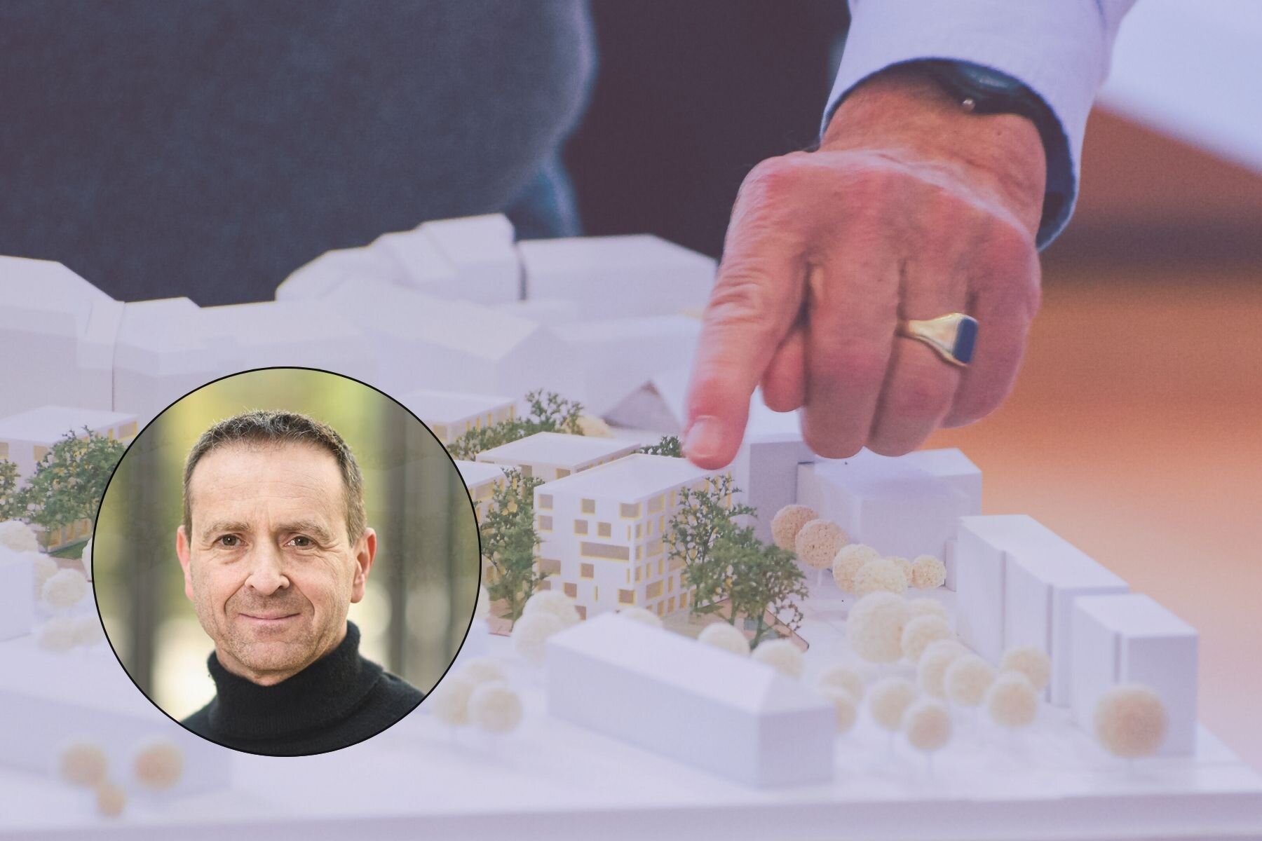 Hand zeigt auf Architekturmodell, Portrait eines Mannes mit schwarzem Rollkragen.
