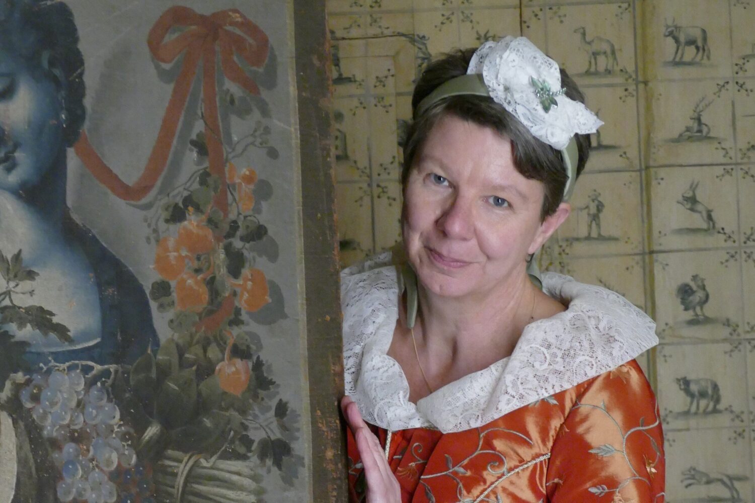 Eine Frau in historischem Kostüm neben einem gemalten Bildnis.