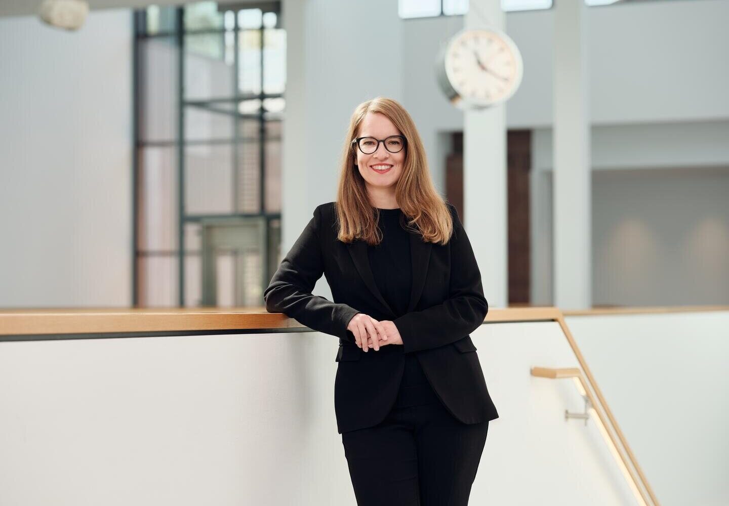 Eine Person steht an einem Geländer, im Hintergrund eine Uhr.