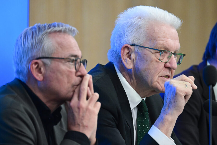 Zwei Männer mit Brillen sitzen nebeneinander vor Mikrofonen.