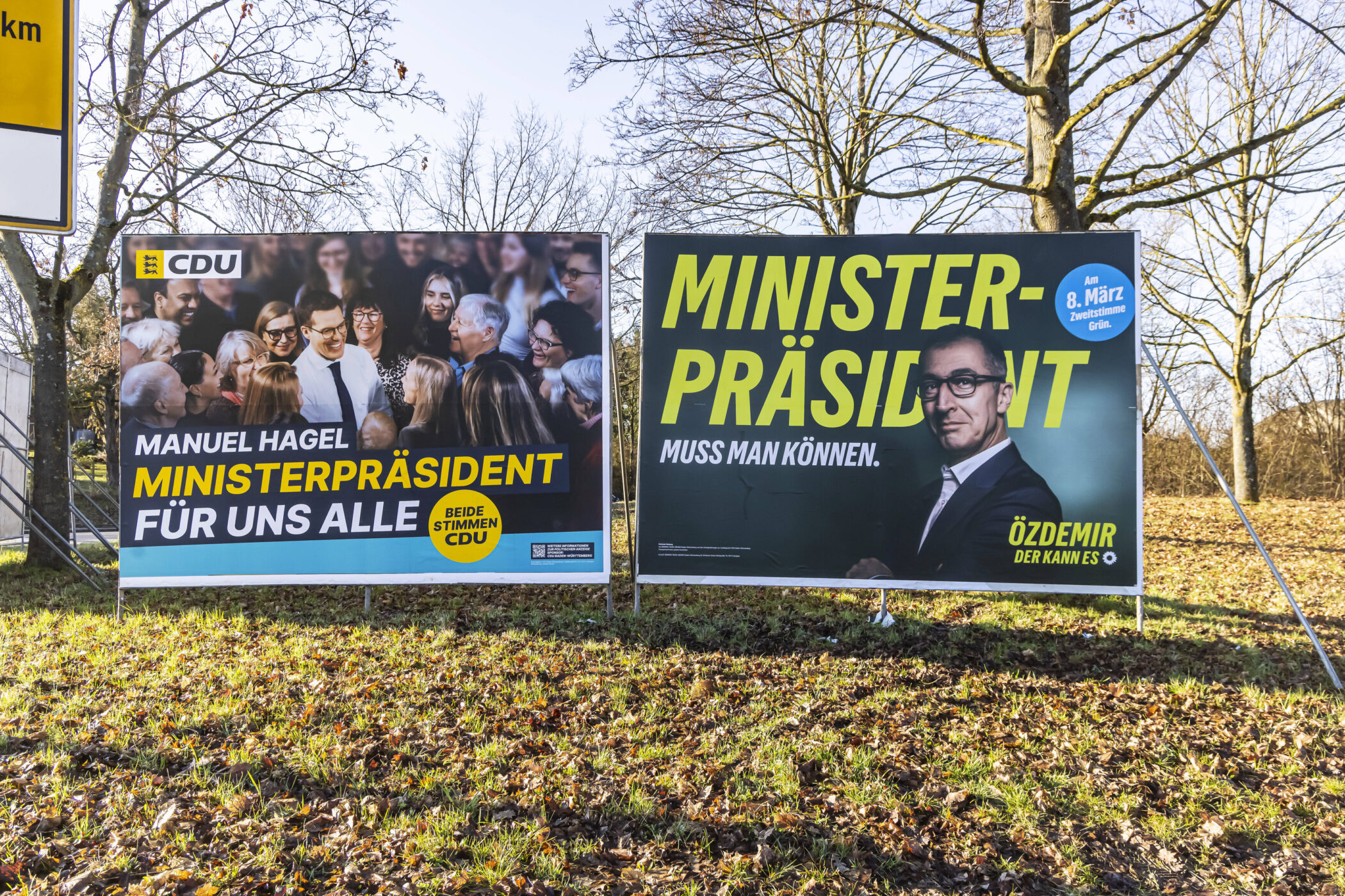 Zwei Wahlplakate von CDU und Grünen auf einer Wiese im Freien.