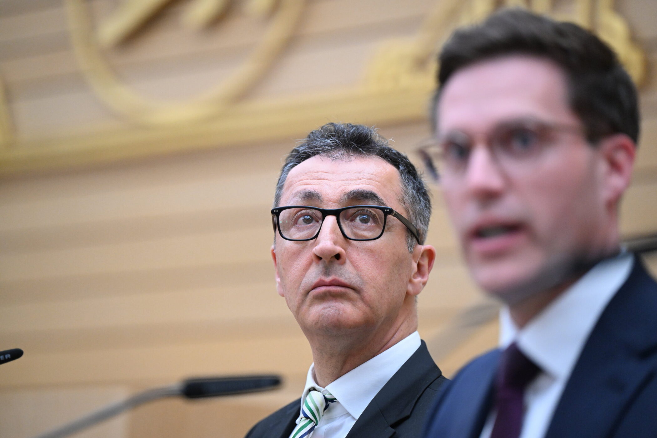 Zwei Männer in Anzügen bei einer Veranstaltung, Fokus auf den Mann links.