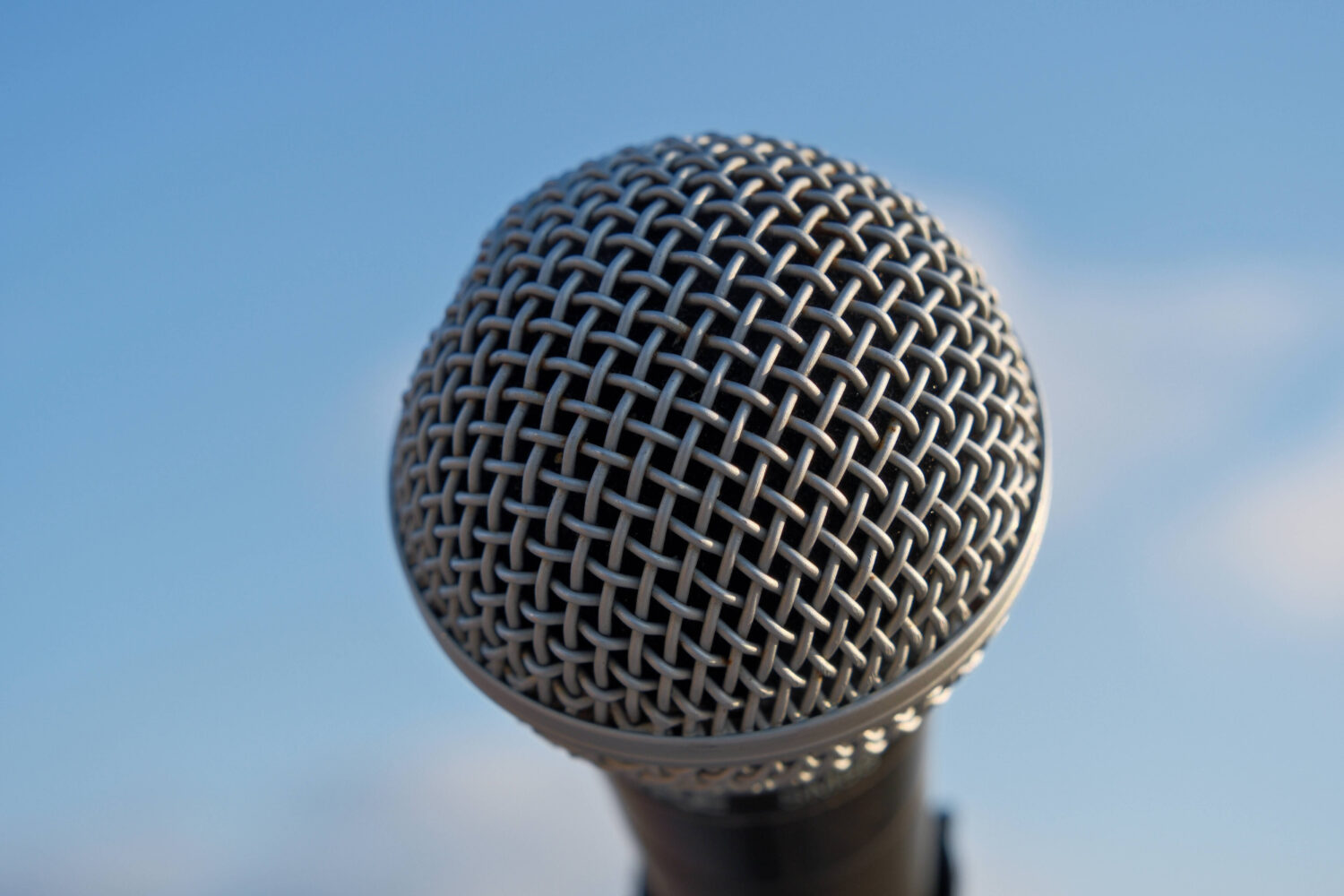 Nahaufnahme eines Mikrofons vor blauem Himmel.