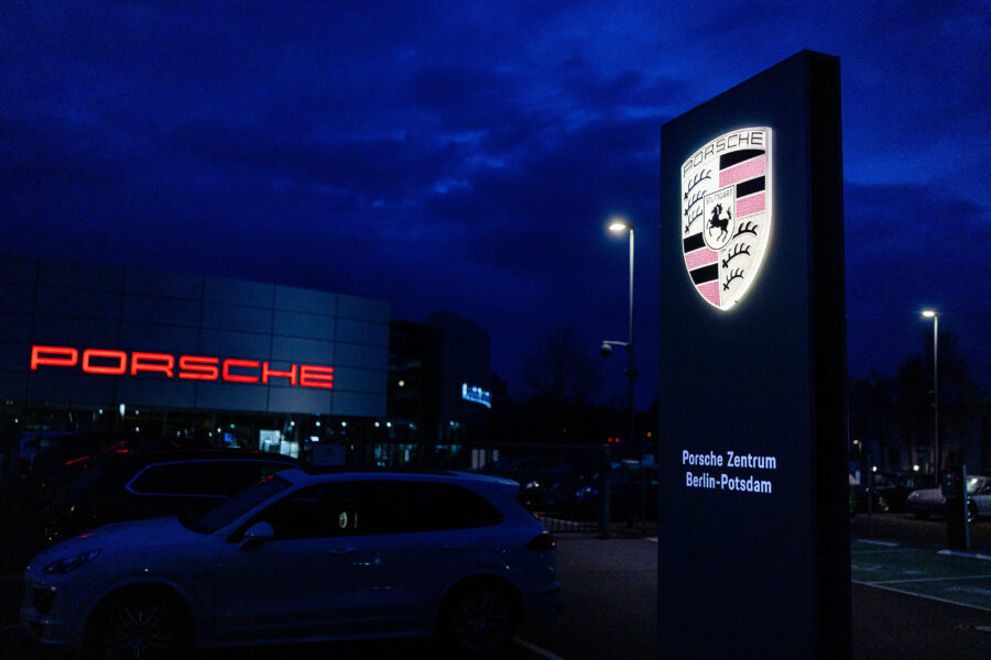 Leuchtendes Porsche-Logo, Schild mit "Porsche Zentrum Berlin-Potsdam", Auto im Vordergrund.