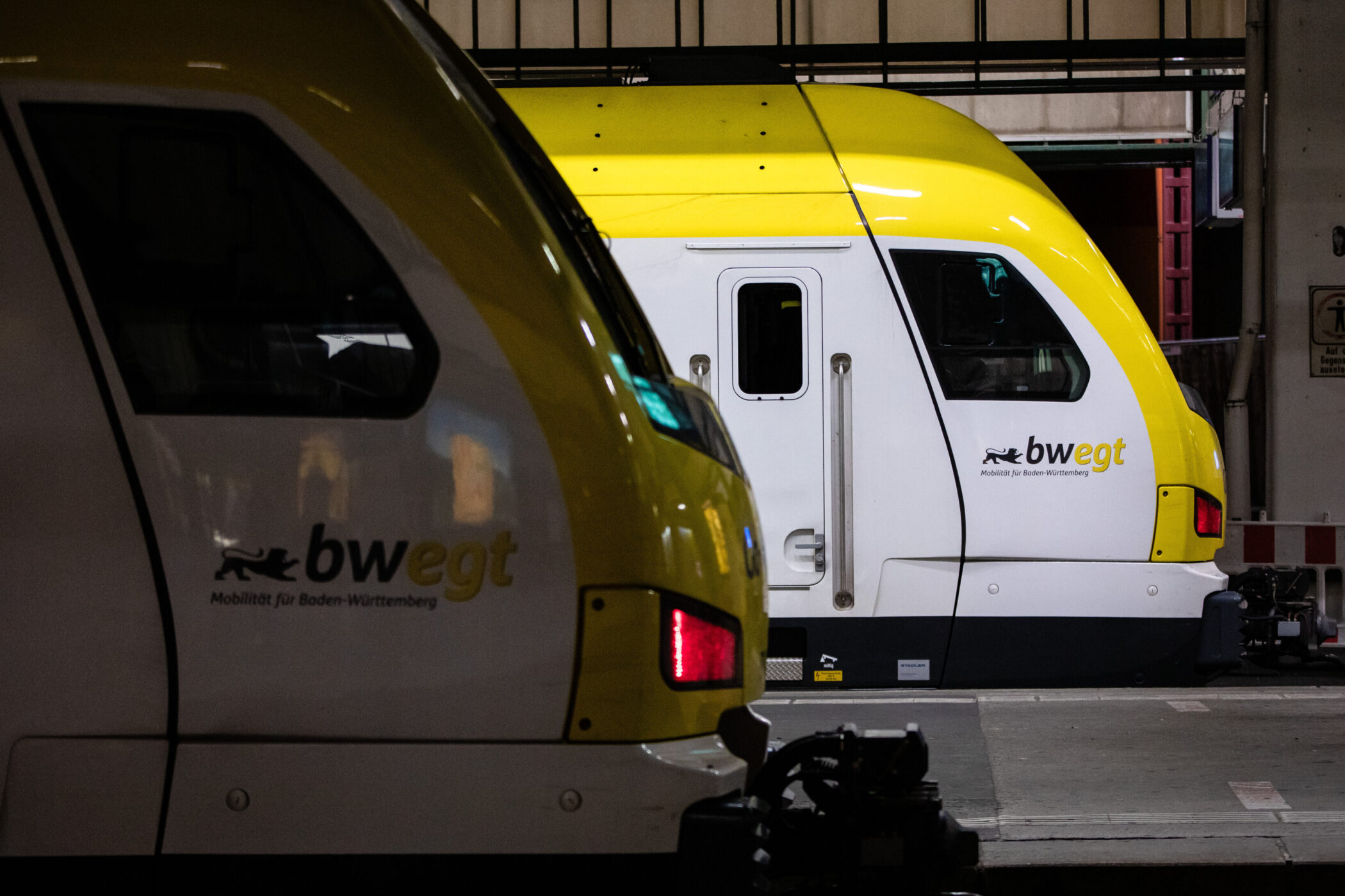Zwei gelb-weiße Züge mit „bwegt“-Logo in einer Halle.