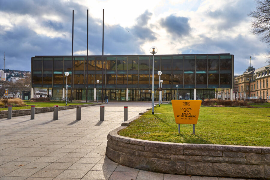 Modernes Gebäude mit Glasfassade, Rasenfläche und Schild: "Landtag von Baden-Württemberg".