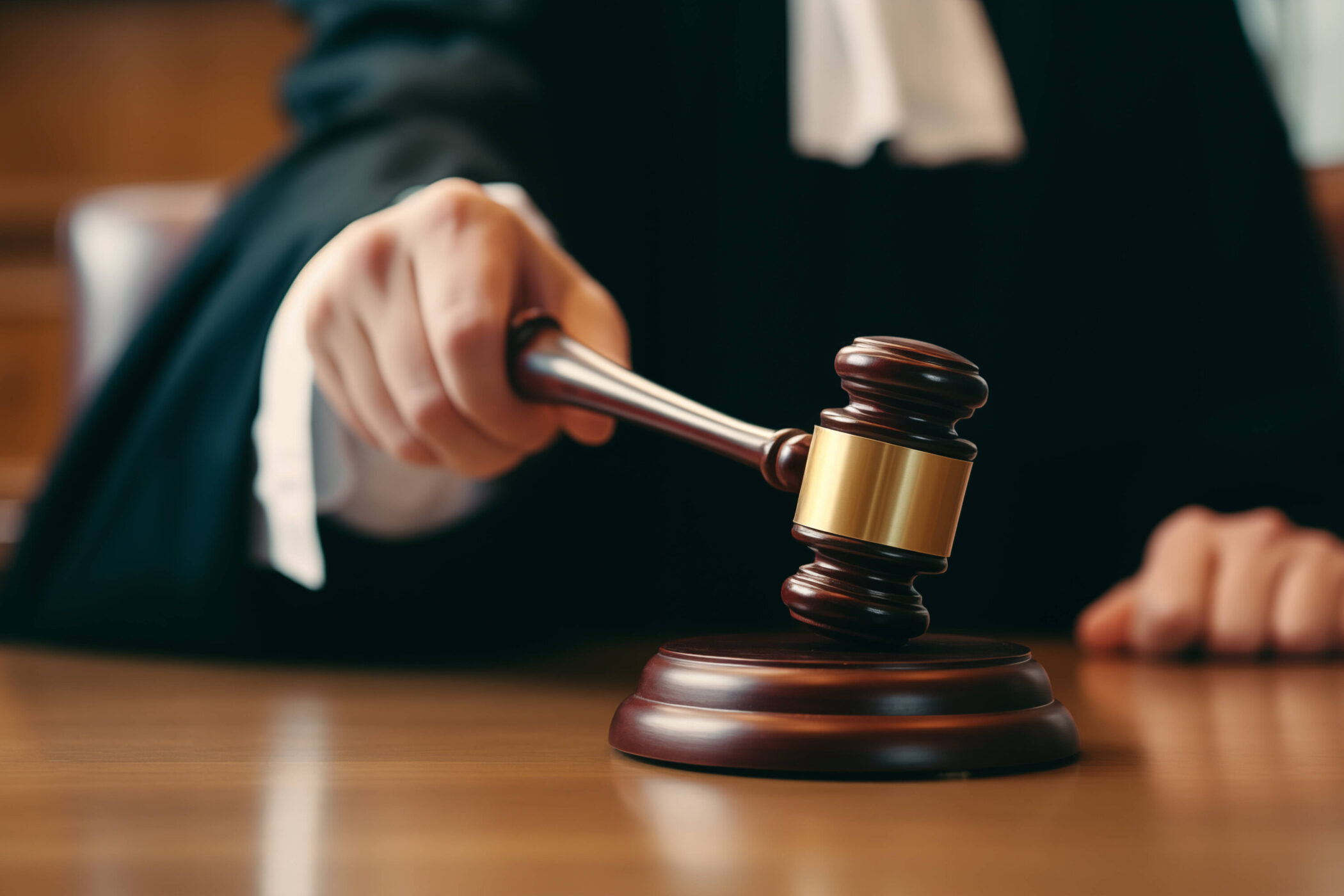 Person schlägt mit Richterhammer auf Holzsockel.