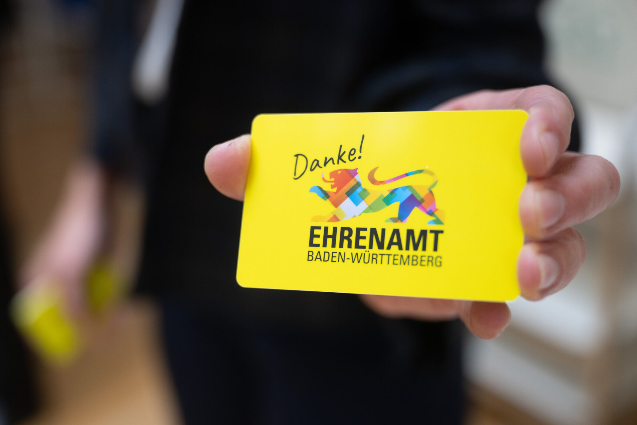 Gelbe Karte mit Aufschrift "Danke! EHRENAMT BADEN-WÜRTTEMBERG", bunte Löwengrafik.