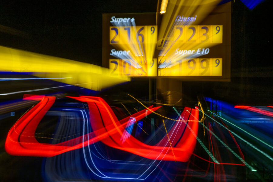 Verschwommene Leuchtschrift mit Tankstellenpreisen und bunten Lichtspuren.