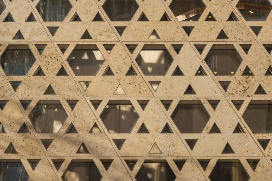 Fassadenstruktur mit dreieckigen und sechseckigen Mustern aus Stein und Glas.