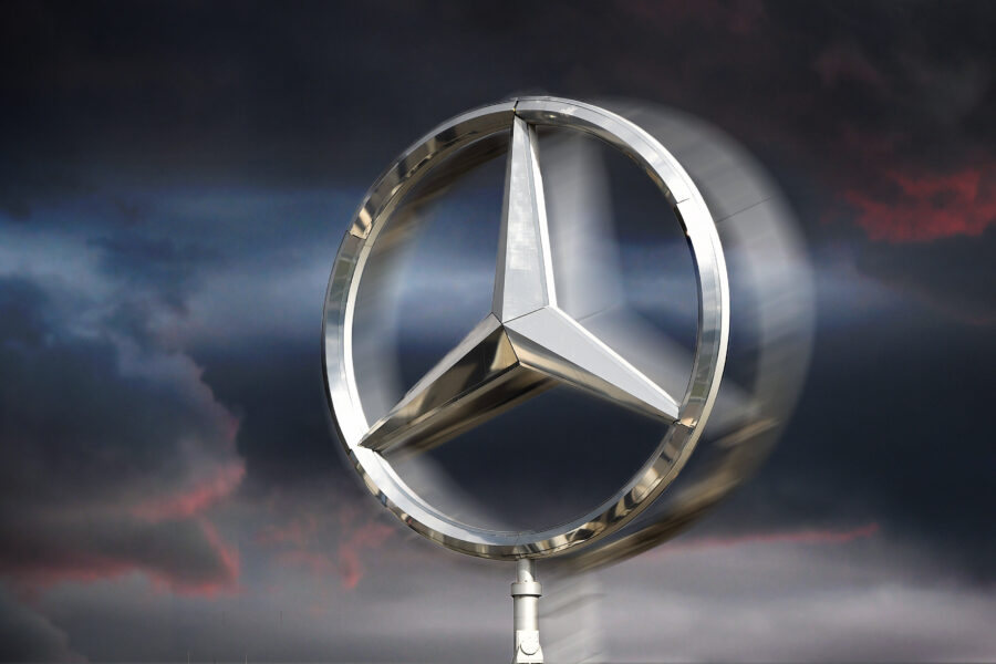 Sich drehender Mercedes-Stern vor bewölktem Himmel.