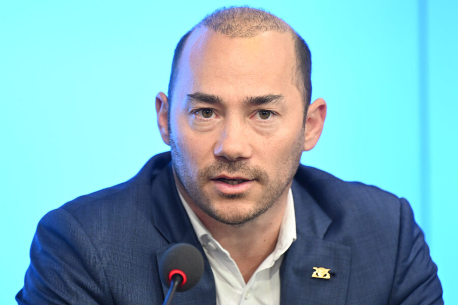 Eine Person spricht in ein Mikrofon vor blauem Hintergrund.