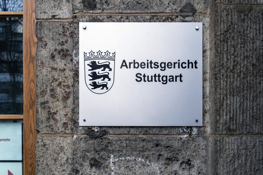 Schild mit Aufschrift "Arbeitsgericht Stuttgart" an einer Steinwand.