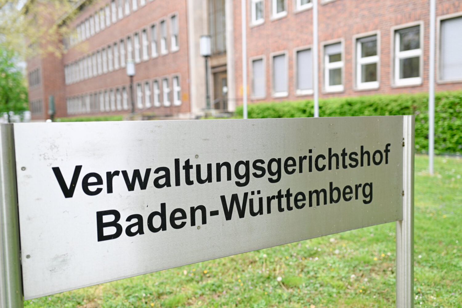 Schild mit Text: „Verwaltungsgerichtshof Baden-Württemberg“ vor Backsteingebäude.