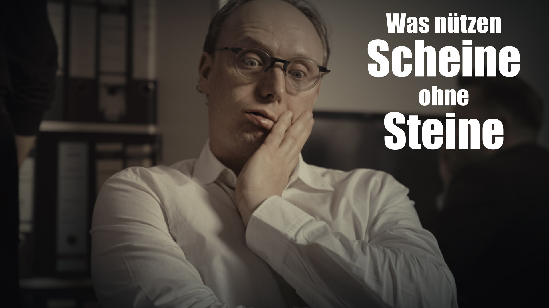 Mann mit Brille stützt Kopf auf Hand; Text: "Was nützen Scheine ohne Steine".