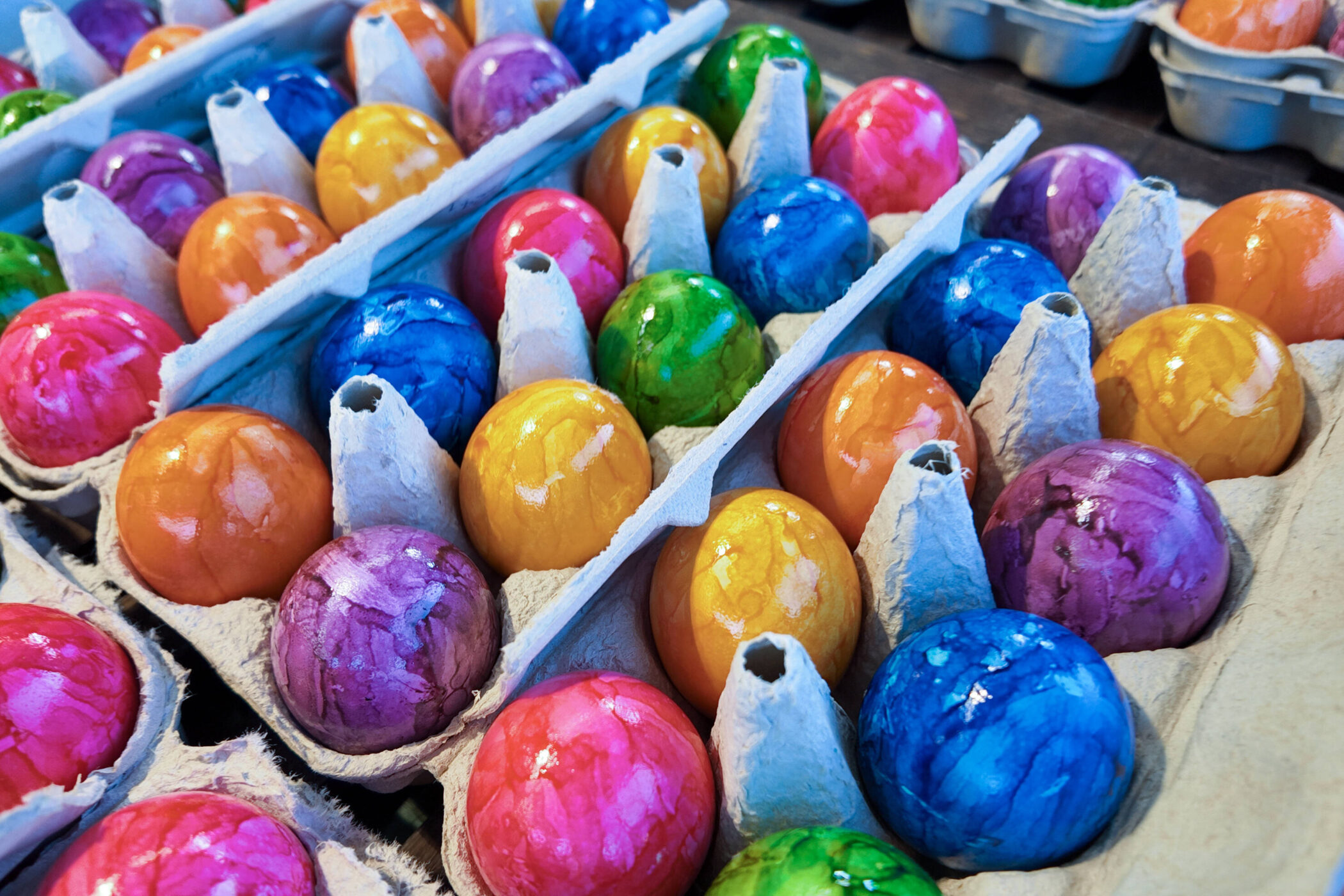 Bunte Eier in Kartonverpackungen aufgereiht.