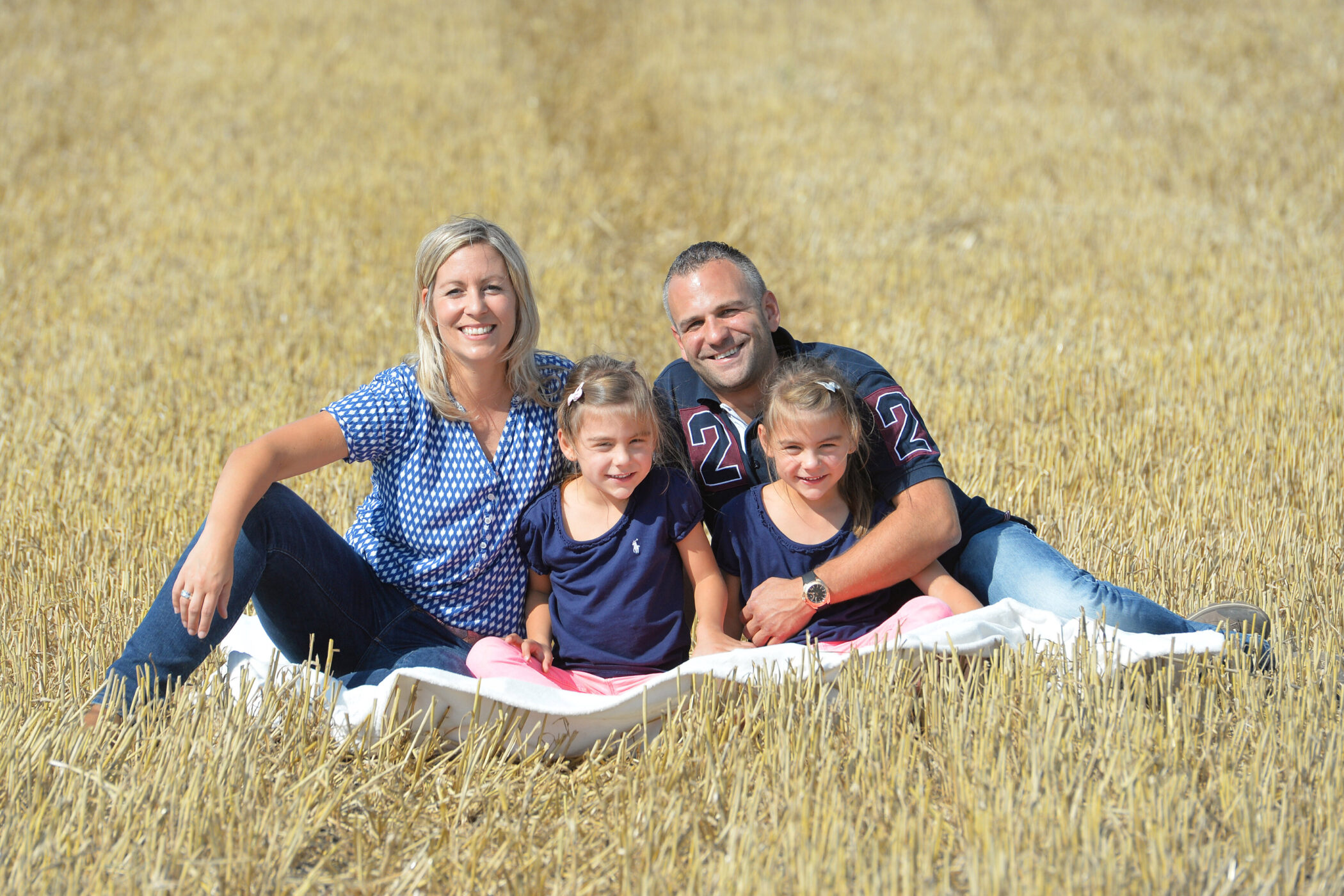 Vier Personen sitzen auf einer Decke im Feld.