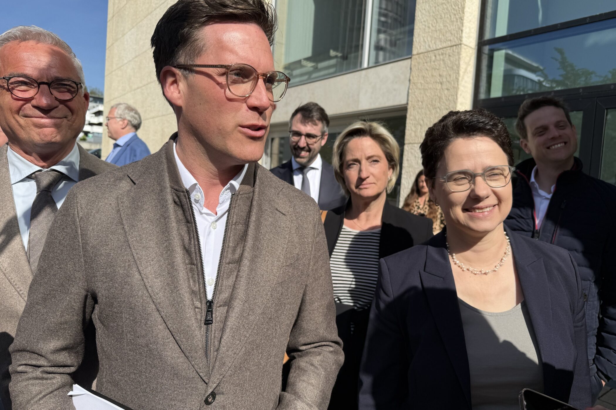 Eine Gruppe von acht Personen im Freien vor einem Gebäude.