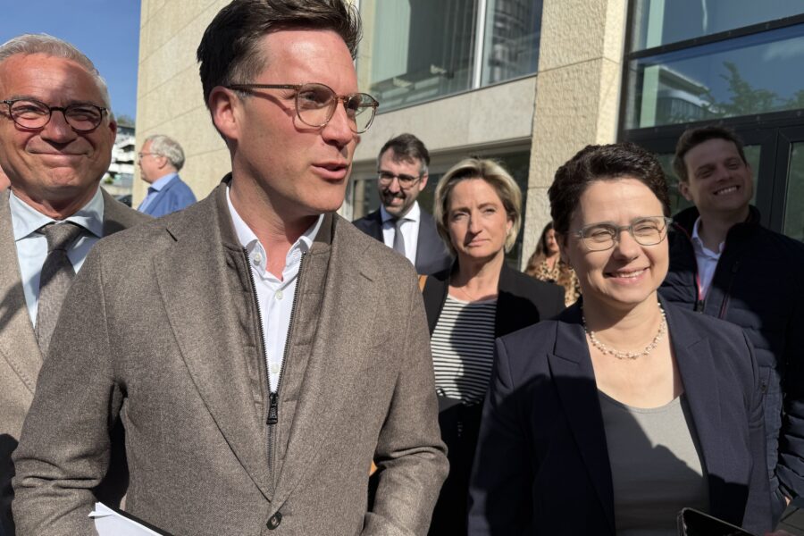 Eine Gruppe von acht Personen im Freien vor einem Gebäude.