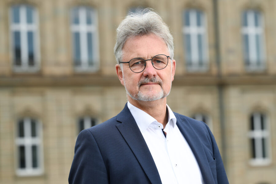 Mann im Anzug vor einem Gebäude mit Fenstern.