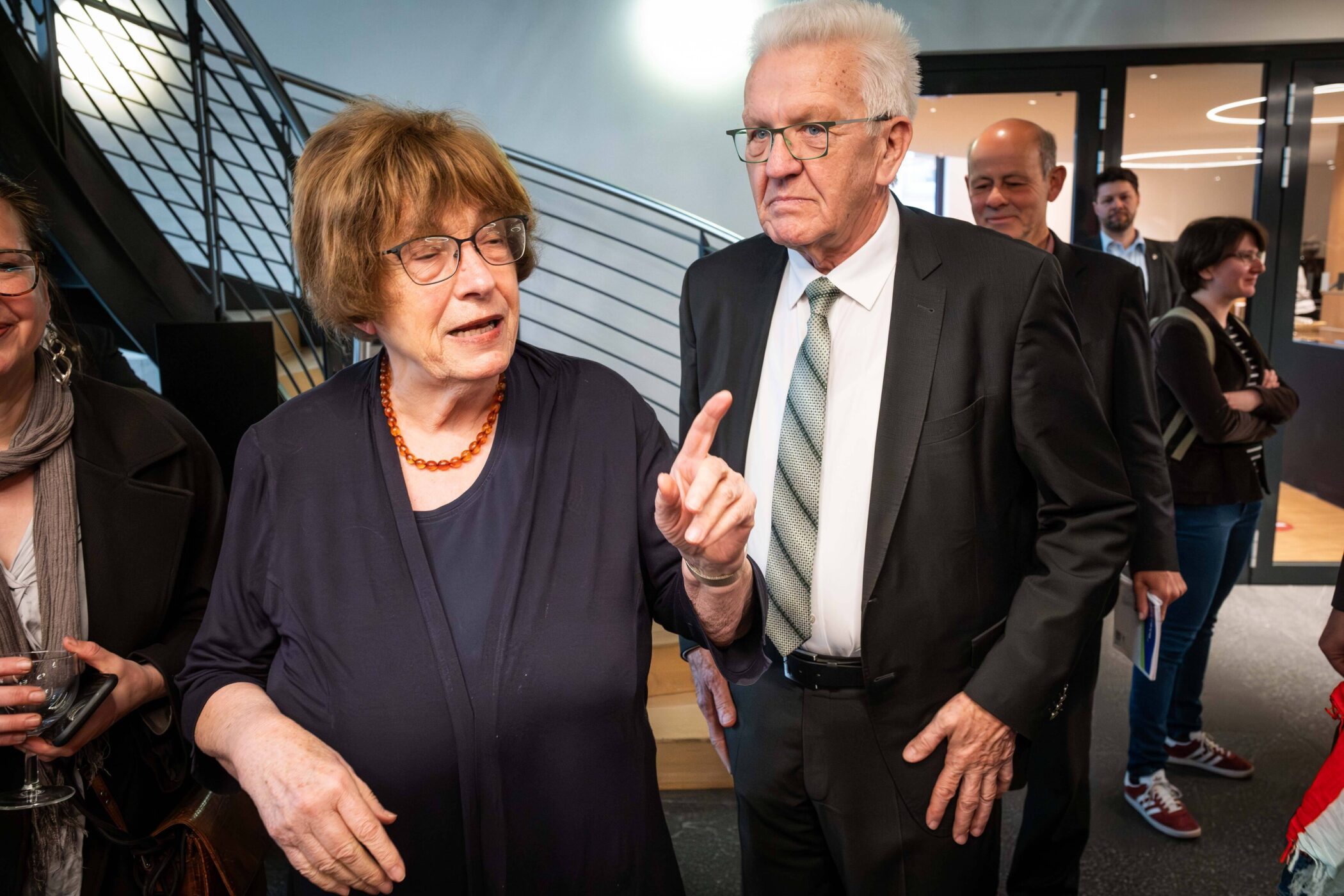 Zwei Personen unterhalten sich, im Hintergrund drei weitere Personen.