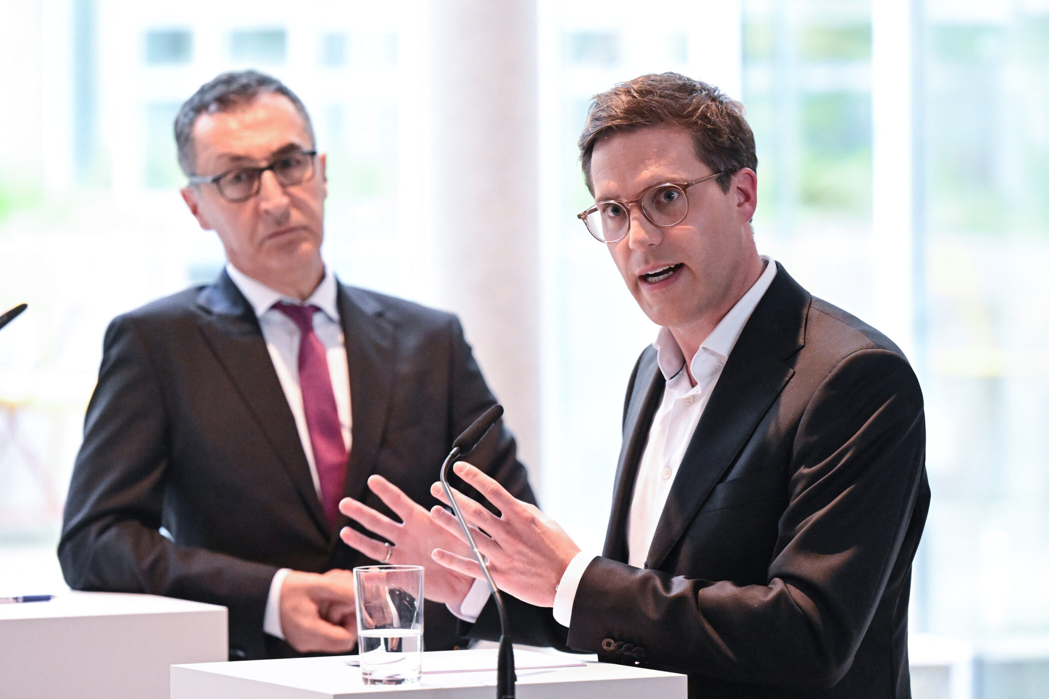 Zwei Männer im Anzug sprechen bei einer Konferenz.